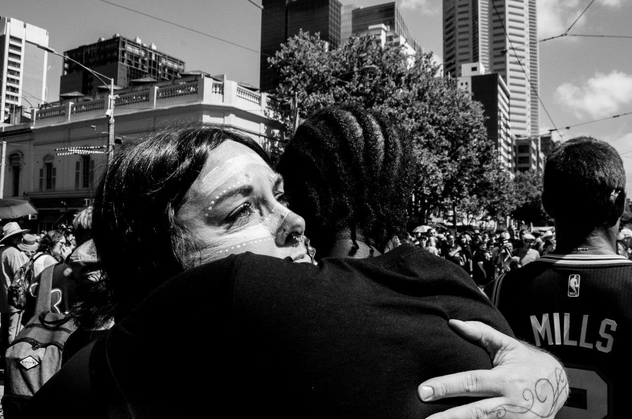 close upp of two aboriginal people hugging during the invasion day protest